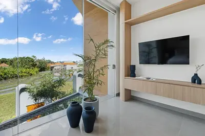a living room with a large window and a tv at New 2BR Architectural Masterpiece in Umalas in Kerobokan