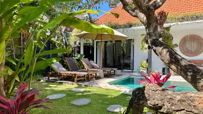a backyard with a pool and chairs and an umbrella at Villa Mint Dua, Peaceful 3BR Villa - Near La favela Seminyak in Seminyak