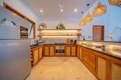 a large kitchen with wooden cabinets and a refrigerator at 7 BR Luxury Oasis in Seminyak in Seminyak