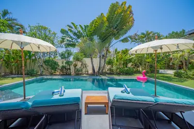 a swimming pool with chairs and umbrellas at 7 BR Luxury Oasis in Seminyak in Seminyak