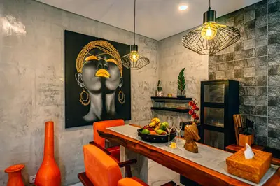 a dining room with orange chairs and a table with a bowl of fruit at Amshiga 5 in Jimbaran