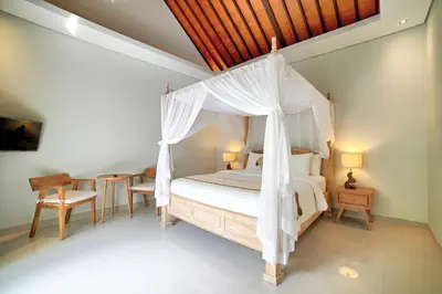 a bedroom with a canopy bed and a table and chairs at Villa LAKSMI in Seminyak