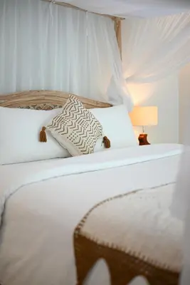 a white bed with two pillows and a lamp at Villa Laskmi Legian in Seminyak