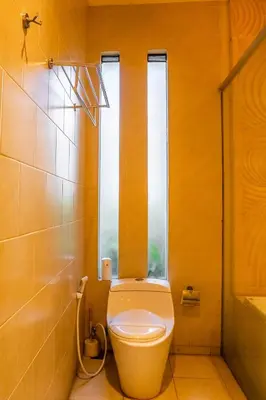 a bathroom with a toilet and a window at Jineng Febe G Villa in Seminyak