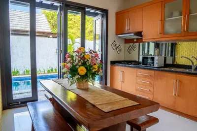 a kitchen with a table with a vase of flowers on it at Jineng Febe G Villa in Seminyak