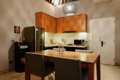 a kitchen with a wooden table and a refrigerator at Urban Villas 5BR in Legian