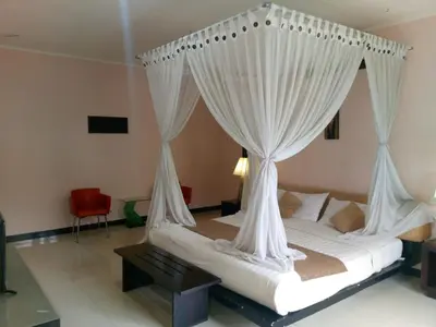 a bed with white curtains in a room at Rishi Villas in Kerobokan