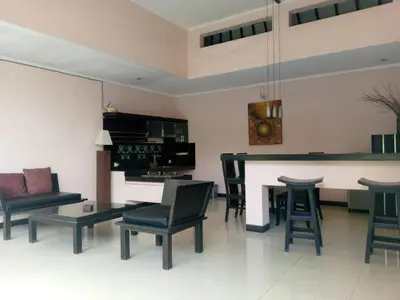 a living room with a table and chairs and a bar at Rishi Villas in Kerobokan