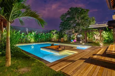 a swimming pool in a yard with a wooden deck at Exclusive 4BR Villa Kito - Cinema, Sauna, Yoga and Pool in Jimbaran