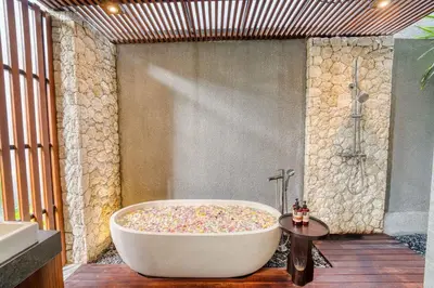 a bath tub in a bathroom with a stone wall at Natadesa Villa 3BR Family Villa in Jimbaran in Jimbaran