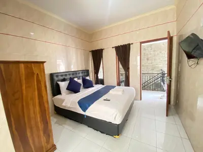 a bedroom with a bed with blue pillows and a balcony at SG Hotel - 2 Minutes to the Beach By Micky Studio 2 in Legian
