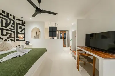 a bedroom with a green bed and a flat screen tv at Villa Aura - Spacious 1BR Private Pool Luxury Villa in Seminyak