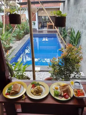 a table with plates of food next to a swimming pool at Nabali Villa in Kerobokan