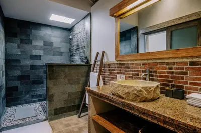 a bathroom with a stone sink and a mirror at Stylish 3BR Villa in Central Berawa Canggu - near Finns in Canggu