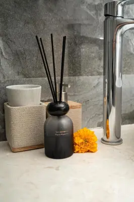 a black vase with sticks in it on a counter at Villa Bella Poppy in Seminyak