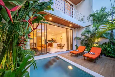 a house with a swimming pool with orange chairs and plants at Villa Boha Seminyak in Seminyak