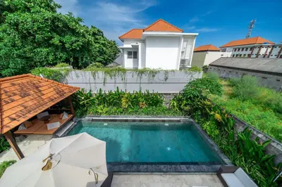 a swimming pool with an umbrella and a house at Villa Sunset-Near Seminyak Pool Free Airport Xfer in Seminyak