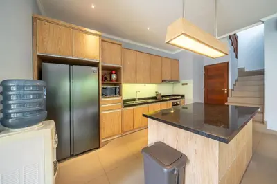 a kitchen with wooden cabinets and a stainless steel refrigerator at Villa Sunset-Near Seminyak Pool Free Airport Xfer in Seminyak