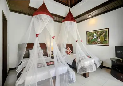 two beds in a bedroom with mosquito nets at Bougenville 4 BR Villa Seminyak CYN in Seminyak