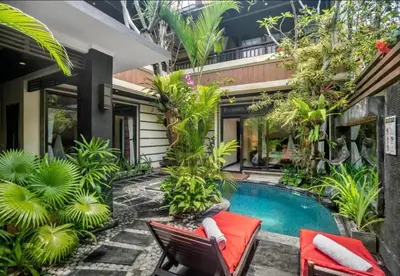 a house with a swimming pool and two chairs and a house at Bougenville 4 BR Villa Seminyak CYN in Seminyak