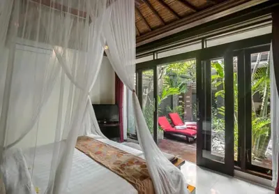 a bedroom with a bed with a mosquito net at Bougenville 4 BR Villa Seminyak CYN in Seminyak