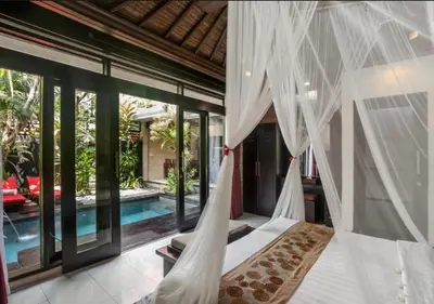 a bedroom with a bed with mosquito nets and a pool at Exquisite 3 BR Villa Seminyak CYN in Seminyak