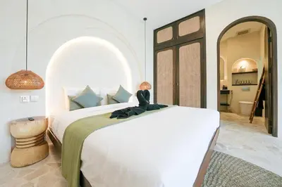 a bedroom with a large bed with a doll sitting on it at Villa Arya 2 in Kerobokan