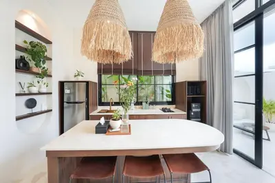 a kitchen with two large chandeliers above a white island at Villa Arya 2 in Kerobokan