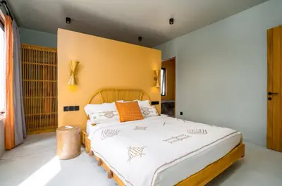 a bedroom with a large bed with white sheets and orange pillows at Villa Javel in Seminyak