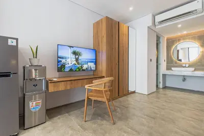 a room with a tv and a chair and a sink at Forseti Athena Managed by ARM One Hundred in Seminyak