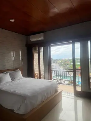 a bedroom with a large bed and a balcony at Brekele Berawa Beachhouse in Canggu