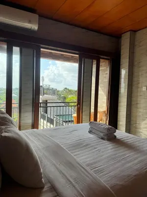 a bedroom with a large bed with a large window at Brekele Berawa Beachhouse in Canggu