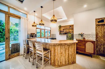 a kitchen with a large wooden bar with stools at Villa Kensington in Seminyak