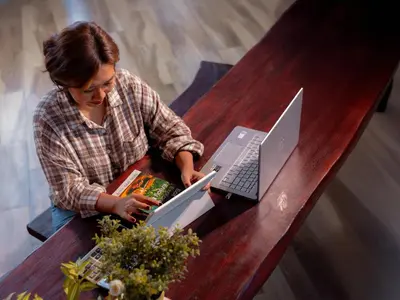 a woman sitting at a table with a laptop at Kuta Cube Hostel in Kuta