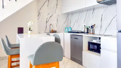 a white kitchen with a counter and a chair at Seminyak Loft 360 Private Pool Villas in Seminyak
