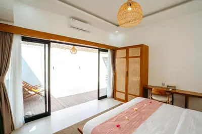 a bedroom with a large bed and a balcony at Villa Tirtha at Nara Villa in Seminyak