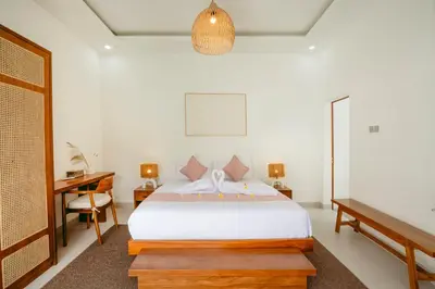 a bedroom with a white bed and a desk and a bed sidx sidx at Villa Tirtha at Nara Villa in Seminyak