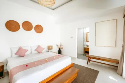 a bedroom with a large white bed with pink pillows at Villa Tirtha at Nara Villa in Seminyak