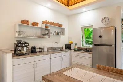 a kitchen with white cabinets and a stainless steel refrigerator at Paradise in the Heart of Seminyak! in Seminyak