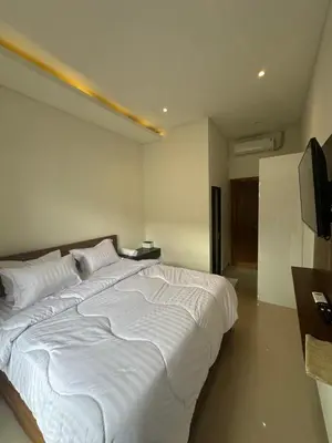 a large white bed in a room with a television at bali thousand island living - guest house in Pesanggaran