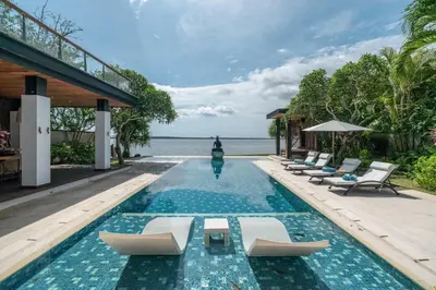 a swimming pool with lounge chairs and the ocean at Beachfront Escape Villa in Ujung