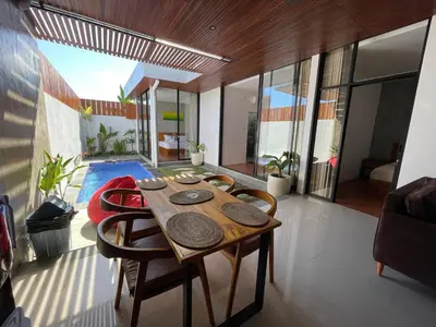 a dining room with a wooden table and chairs at Ozzy Bali Villa 3 in Seminyak