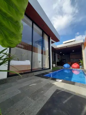 a swimming pool in front of a house at Ozzy Bali Villa 3 in Seminyak