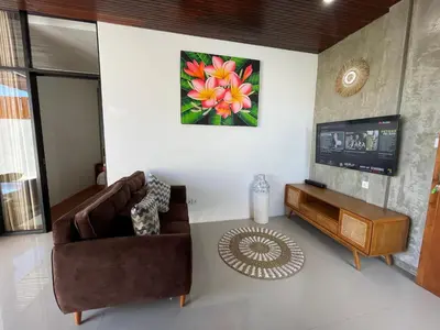 a living room with a couch and a tv at Ozzy Bali Villa 3 in Seminyak