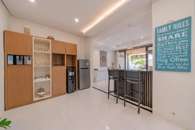 a kitchen with a bar with stools and a refrigerator at Adamo villa Seminyak in Seminyak