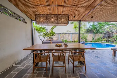 a dining room with a table and chairs and a pool at Adamo villa Seminyak in Seminyak
