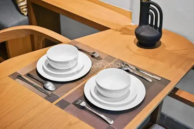 a table with white plates and spoons on it at Aranya by Kozystay - Nusa Dua in Nusa Dua