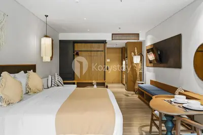 a bedroom with a large bed and a table at Aranya by Kozystay - Nusa Dua in Nusa Dua
