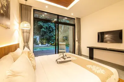 a bedroom with a large white bed and a television at Stylish 5BR Designer Villa, 400m to the Ocean in Canggu