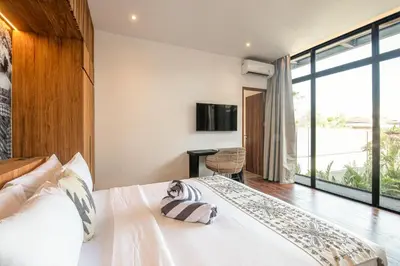 a bedroom with a large white bed and a large window at Elegant 5BR Tropical Escape Just 400m to Beach in Canggu